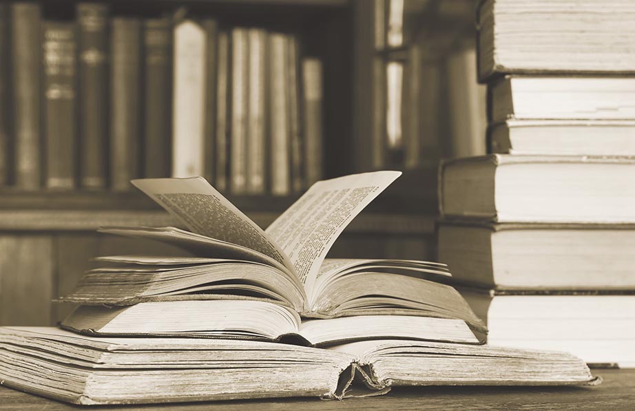 A stack of old books that are spread open, signifying poetry